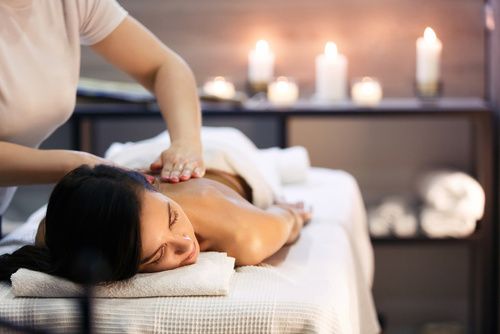 Körpermassage und Wellnessbehandlung im modernen Salon mit Kerzen