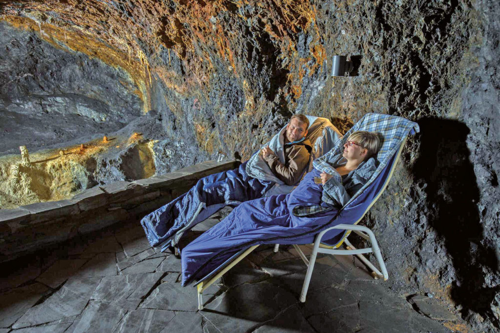 Ein Mann und eine Frau liegen im Heilstollen der Saalfelder Feengrotten in Liegestühlen