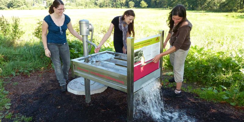 Wanderer probieren eine Station auf dem Feuchtwiesen-Erlebnispfad in Frammersbach im Spessart aus