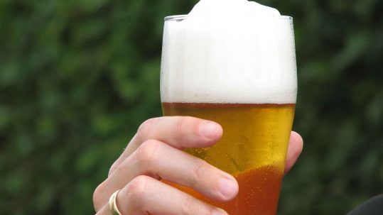 Eine Hand hält ein Glas mit Bier