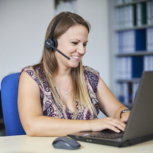 Frau mit Laptop und Headset