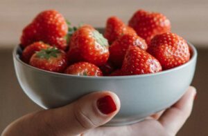 Hand hält Schale mit Erdbeeren