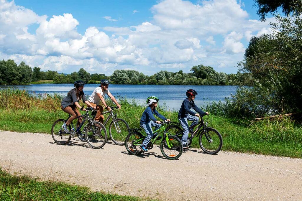 Eine Familie mit zwei Kindern fährt Rad auf dem MainRadweg entlang des Mains.