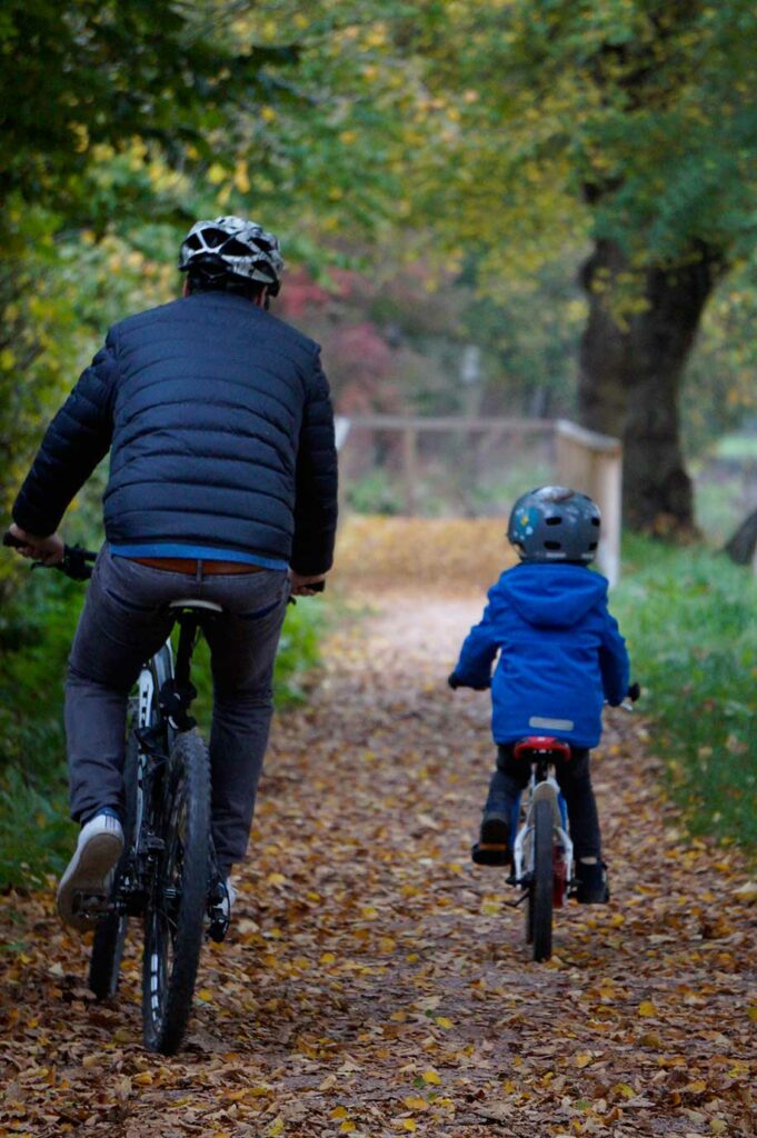 Vater und Sohn fahren auf Fahrrädern in Richtung Donauursprung in Donaueschingen.