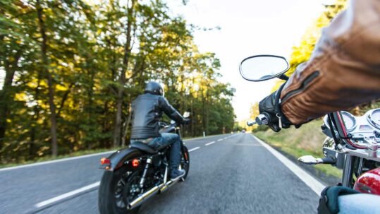 Foto von zwei fahrenden Motorrädern auf der Straße, mit dem Rücken zur Kamera