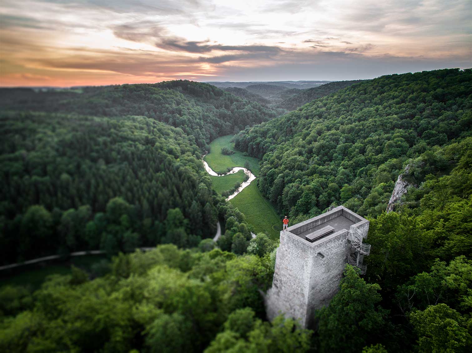 Foto vom Großen Lautertal aus der Vogelperspektive. Man sieht auch die Burgruine Wartstein, auf der ein Wanderer ins Tal blickt.