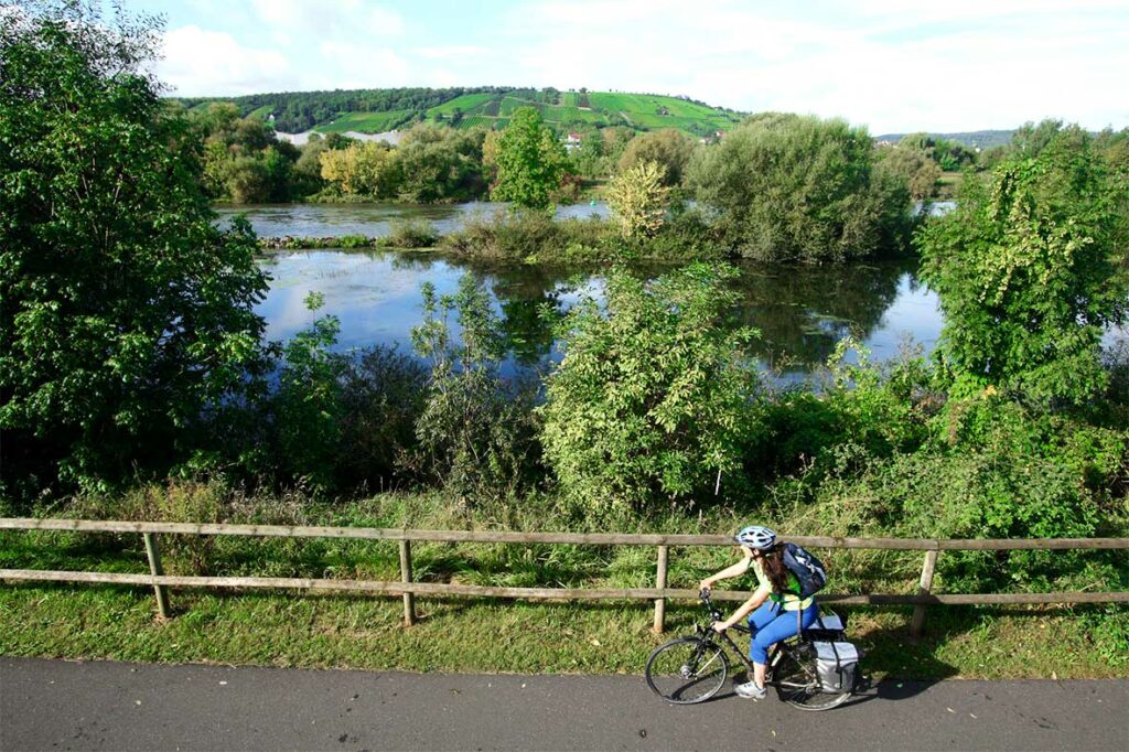 Radfahrerin fährt mit ihrem Rad auf dem MainRadweg entlang des Mains.