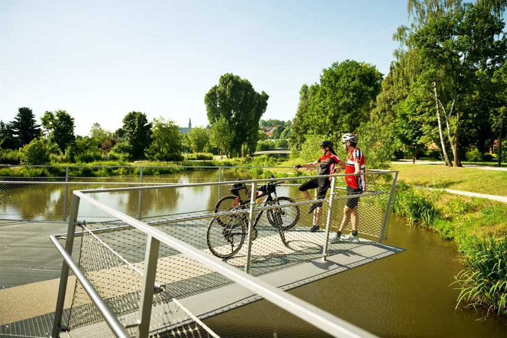 Radfahrer stehen an der Brücke über dem Fischpass im ERBA-Park in Bamberg