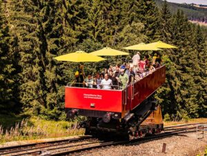 Fahrgäste fahren im Cabrio-Wagen der Thüringer Bergbahn im Schwarzatal. Sie ist eine der steilsten Standsteilbahnen der Welt.