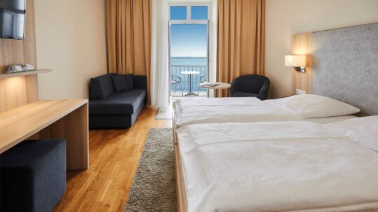 Foto von einem Zimmer im Flair Hotel Zum Schiff am Bodensee. Die Balkontür ist geöffnet und man hat einen schönen Blick auf den See.
