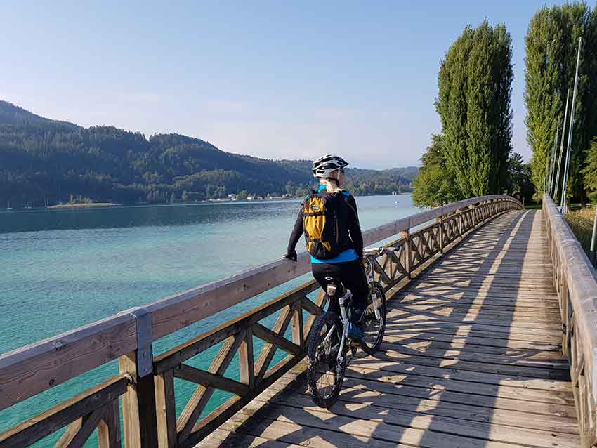 Radfahrer macht Pause auf einer Brücke über den Wörthersee
